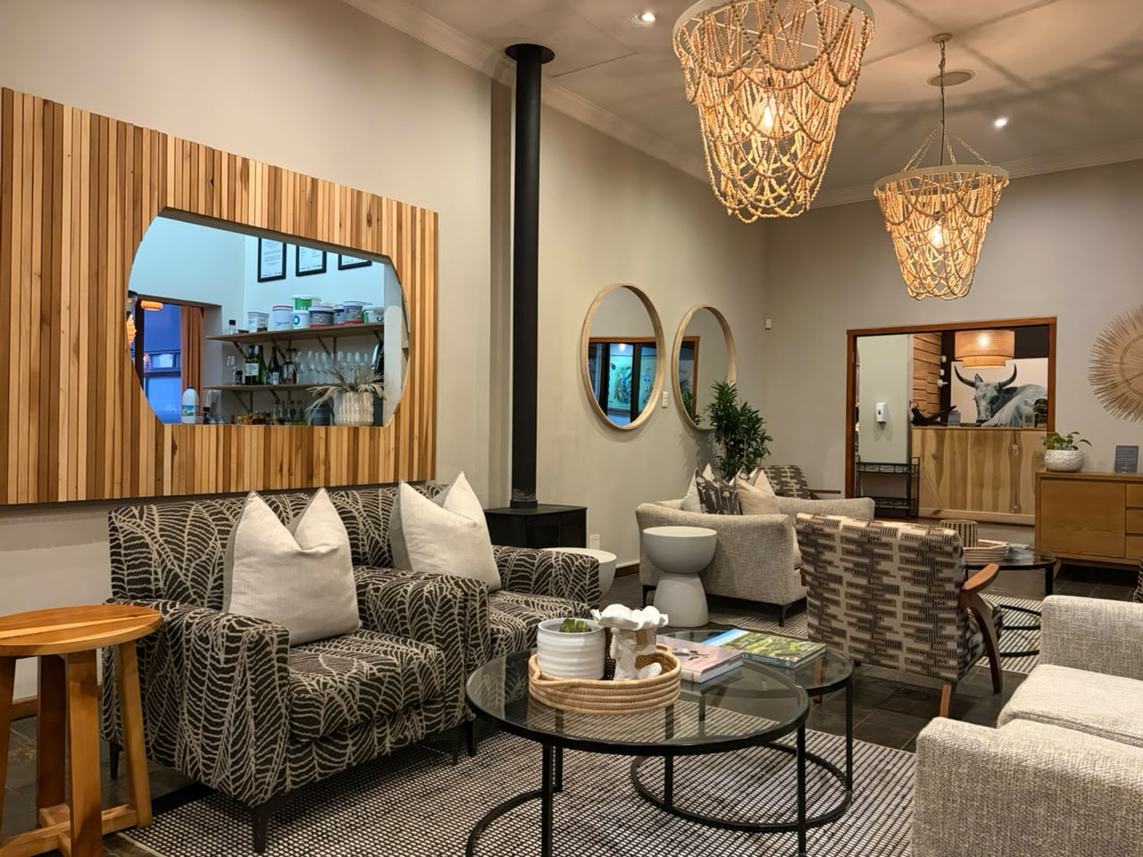 The lounge at Brahman Hills — beaded chandeliers, slatted wood accents, and a fireplace for Midlands winter