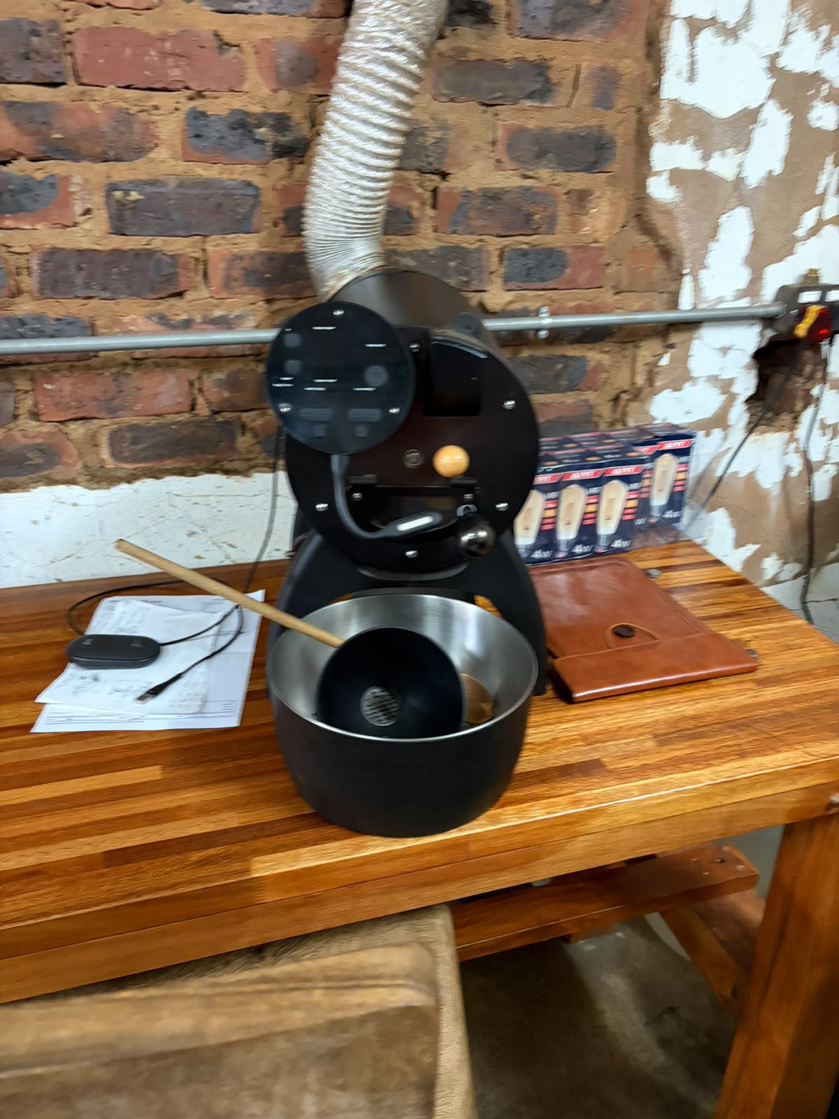 The sample roaster on a wooden workbench — a compact tabletop unit used for test batches before scaling to the Genio
