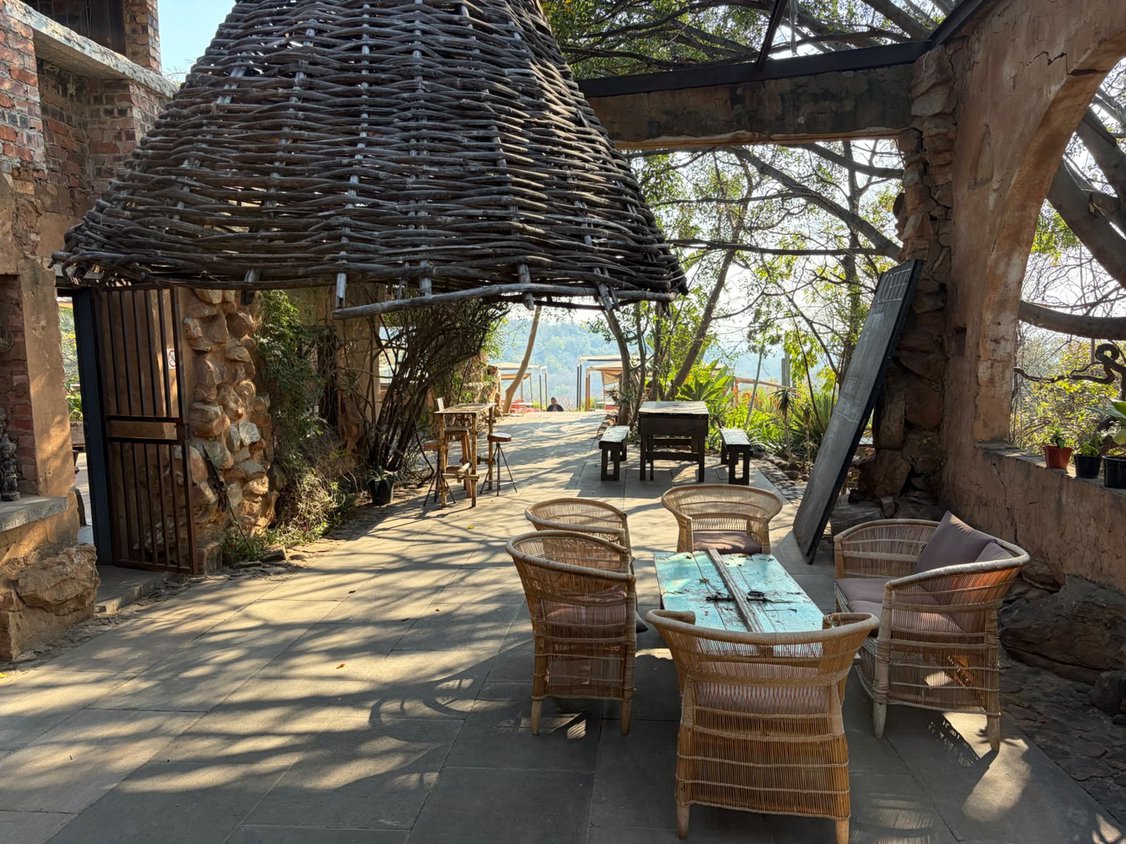 Wicker chairs and a reclaimed turquoise table under a massive woven lampshade at Sorcery's The Ruins café