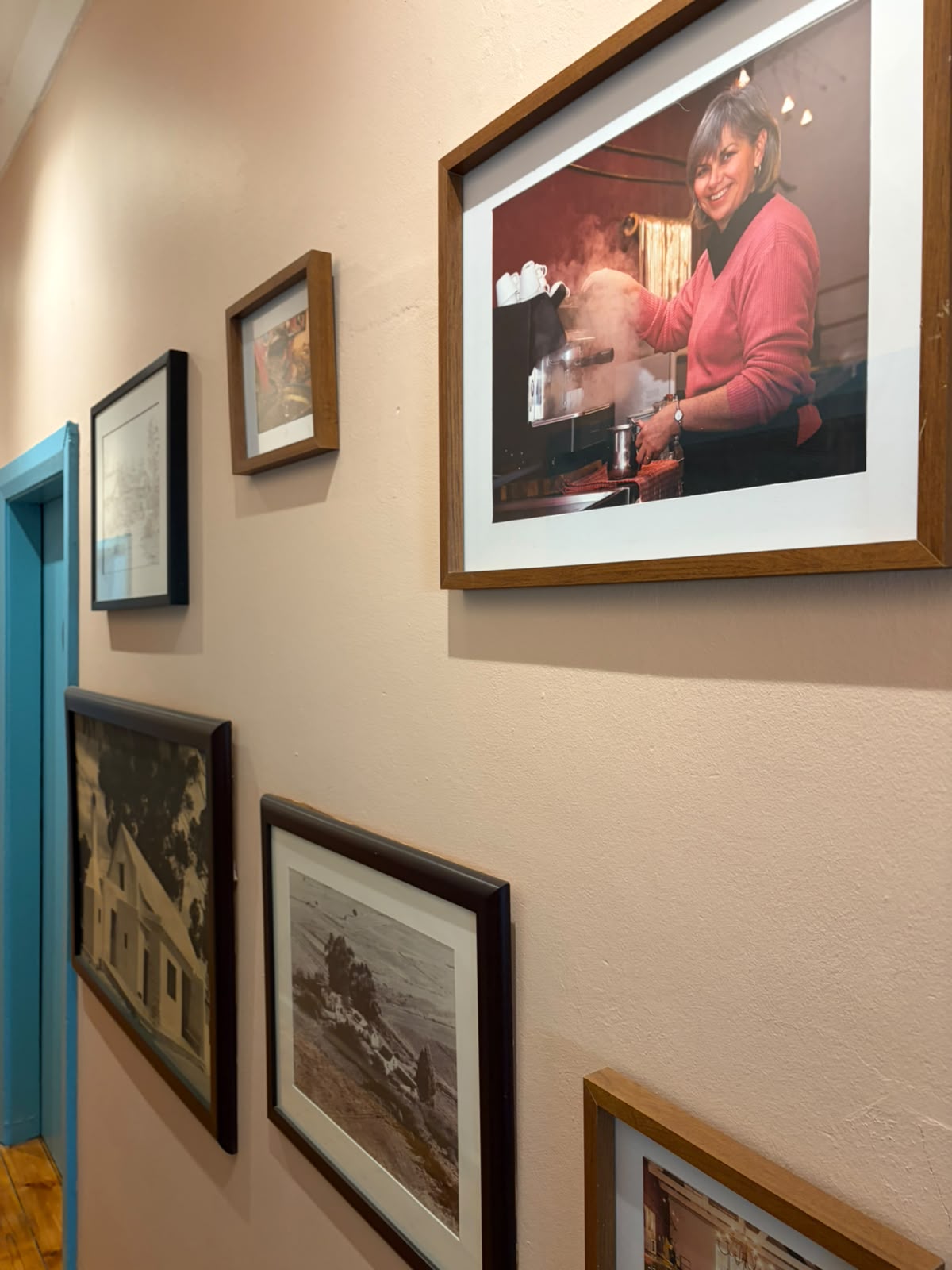 Gallery wall with framed portrait of woman making espresso, historical Midlands photographs, pencil sketches