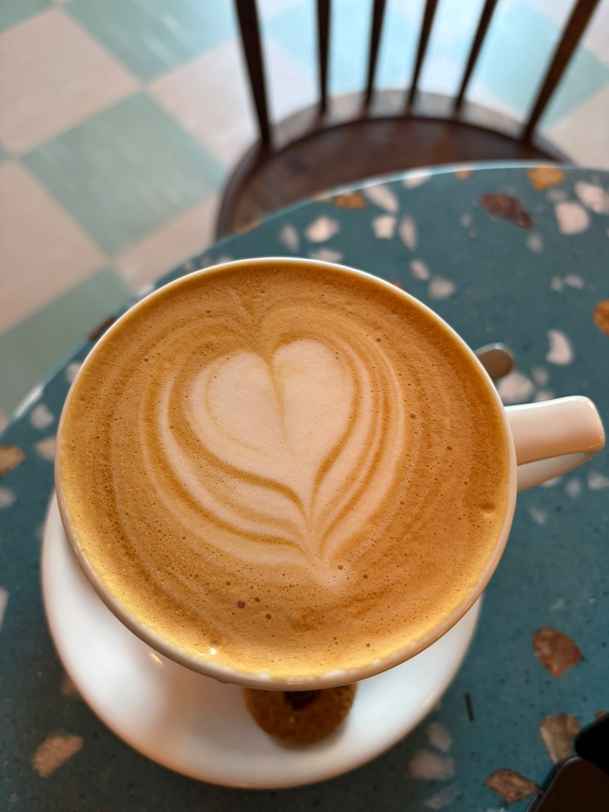 Flat white with heart latte art, overhead view on terrazzo table — golden crema, clean pour