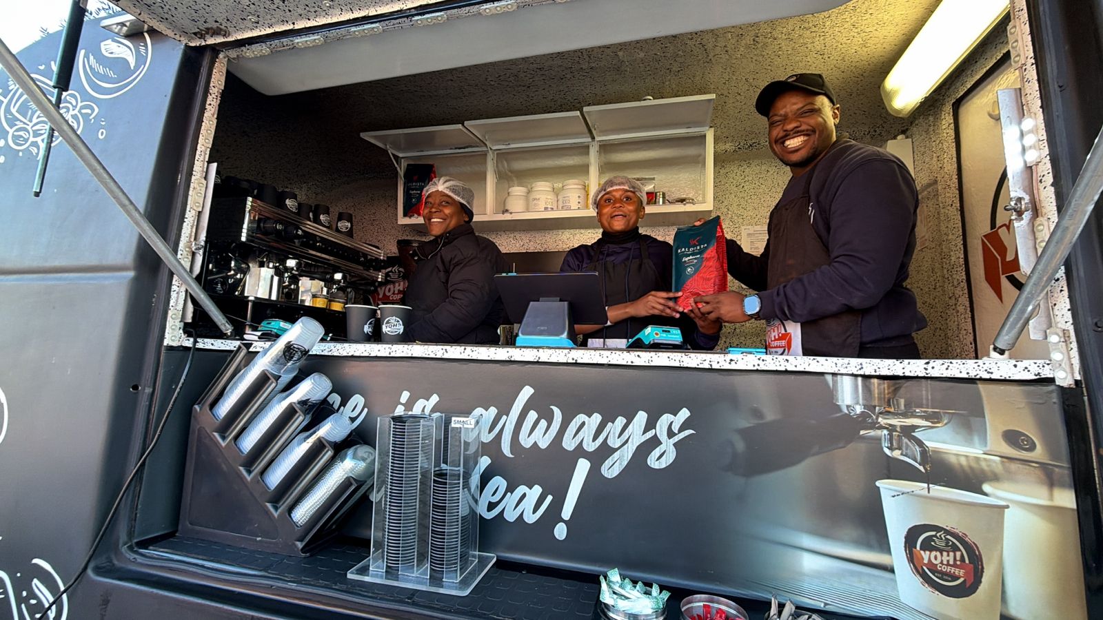 The Yoh Coffee team smiling behind the counter of their mobile coffee truck at Ellis Park