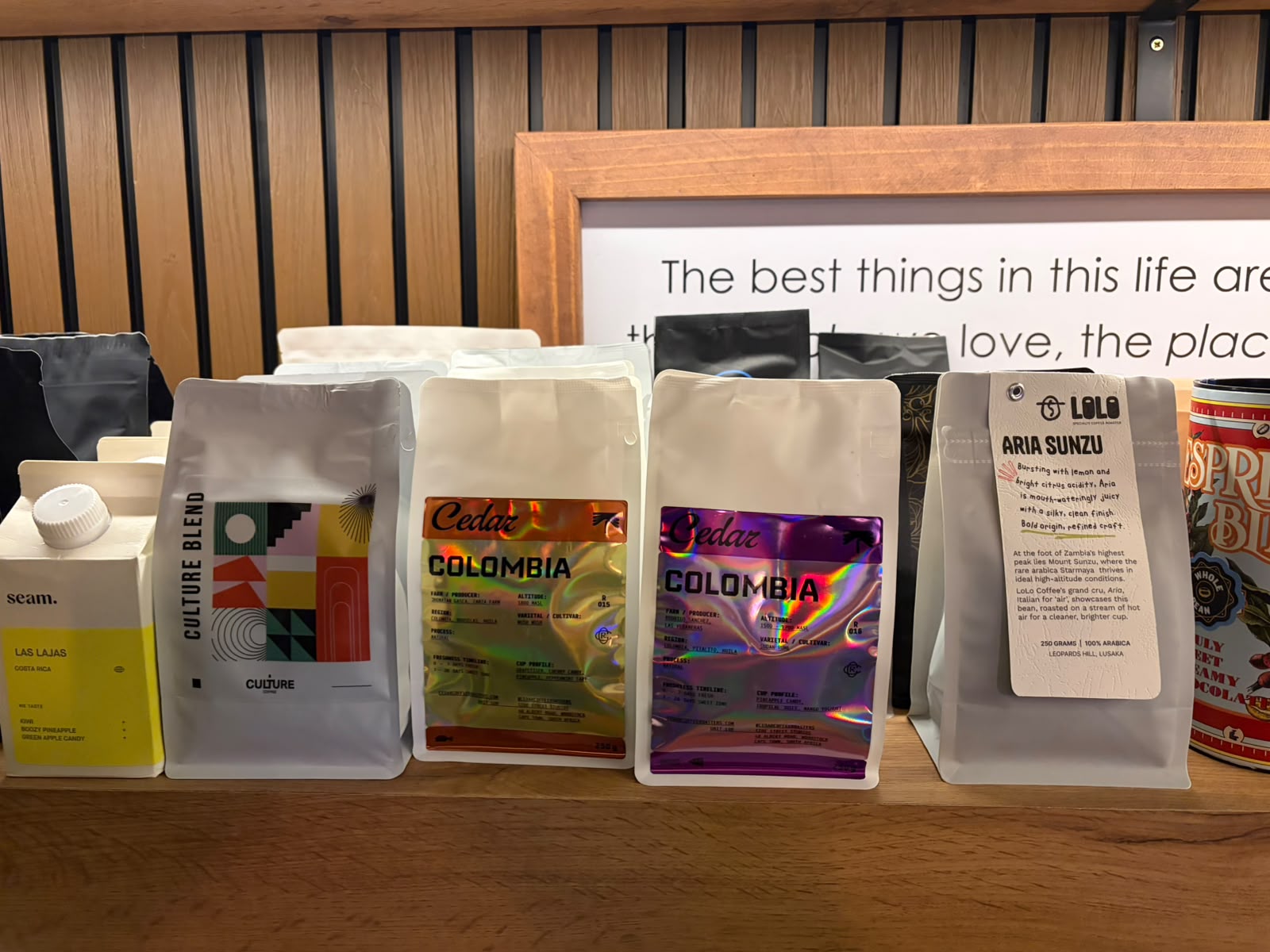 Close-up of Cedar Colombia single-origin bags next to Seam, Culture, and Lolo Aria Sunzu on a wooden shelf