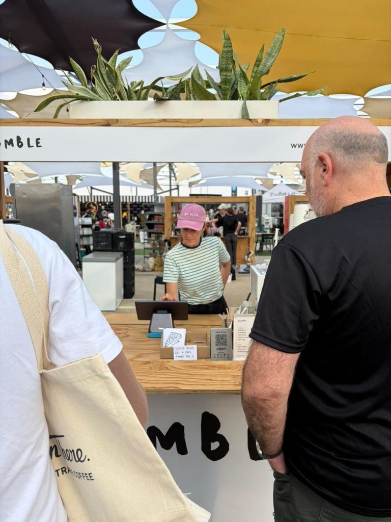 A Humble Coffee barista in a pink cap and green-striped shirt at the counter at the Jo'burg Coffee Festival